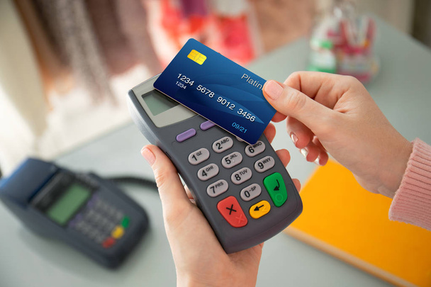 Woman hand holding plastic card and pay pass online terminal - Foto, Imagem