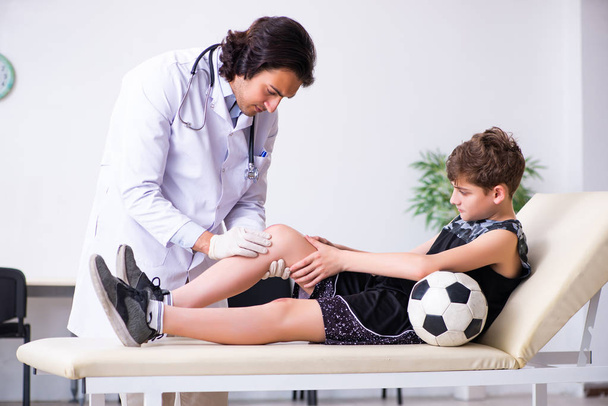 Niño jugador de fútbol visitando joven médico traumatólogo
   - Foto, Imagen