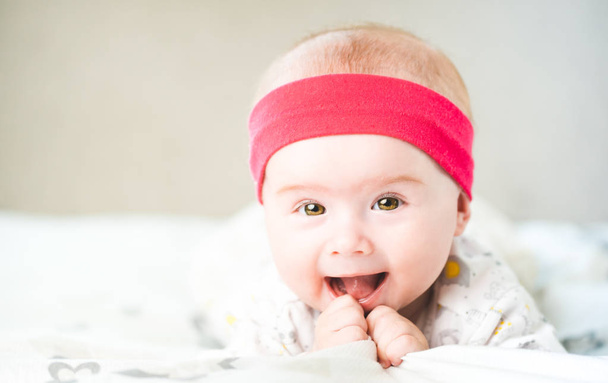 Adorabile bambina con fascia rossa che guarda verso la fotocamera e sorride. Concetto sanitario
 - Foto, immagini