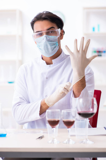 Male chemist examining wine samples at lab - Photo, Image