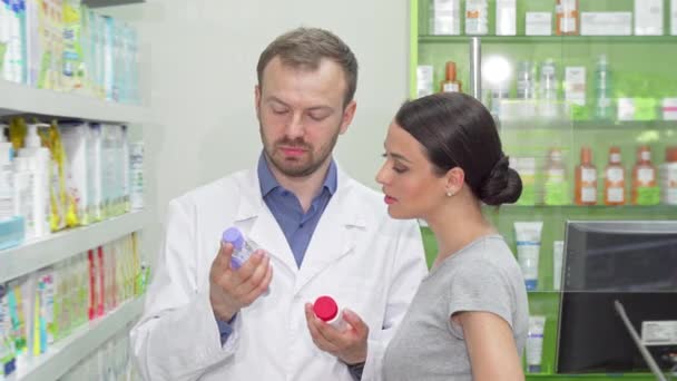 Reifer männlicher Chemiker hilft seiner Kundin bei der Wahl zwischen zwei Artikeln - Filmmaterial, Video
