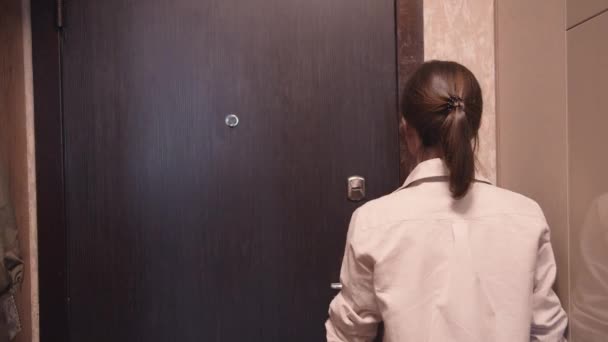 Młoda dziewczyna otwiera drzwi do mieszkania - Materiał filmowy, wideo