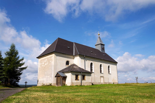 Classicist Church of Holy Trinity from 1783 in Maly Haj, Hora Svate Kateriny town, Most district, Usti nad Labem region, Krusne hory, Ore Mountains, Czech Republic, sunny summer day, clear blue sky background - Photo, Image