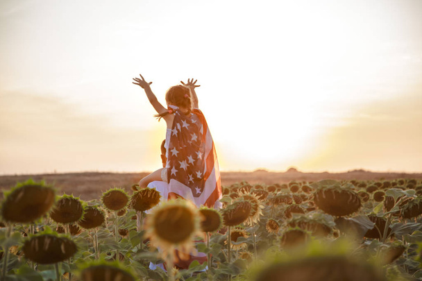 uma menina segura uma bandeira americana ao pôr do sol
 . - Foto, Imagem