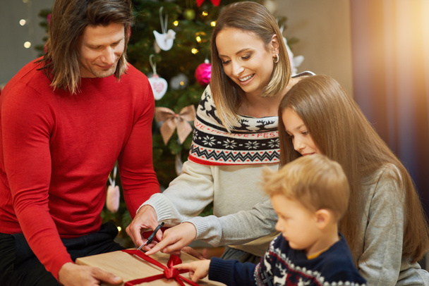 クリスマスツリーの上にプレゼントを持つ美しい家族 - 写真・画像