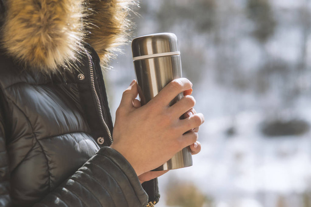 hot tea or coffee out of thermos in woman hands  on winter fores - Foto, immagini