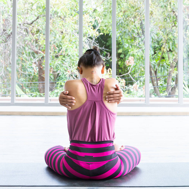 Belle femme asiatique portant des vêtements de sport, pantalon rayé, jouant au yoga dans la chambre, se sentant détendu, heureux et en bonne santé
. - Photo, image