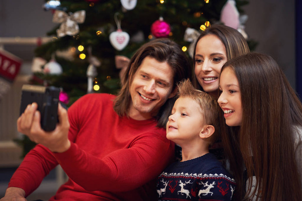 Όμορφη οικογένεια γιορτάζει τα Χριστούγεννα στο σπίτι και λήψη στιγμιαίες εικόνες - Φωτογραφία, εικόνα