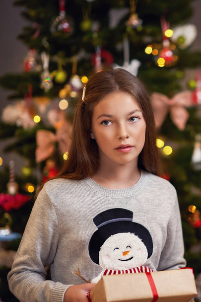 Beautiful girl with present over Christmas tree - Zdjęcie, obraz