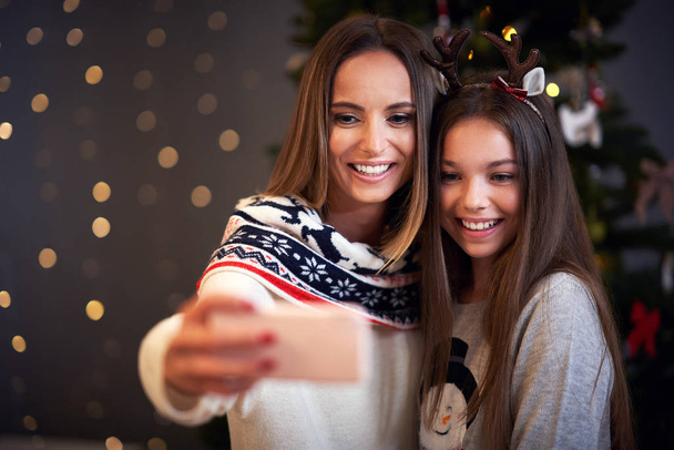 Mother and daughter celebrating Christmas at home and taking selfie - Zdjęcie, obraz