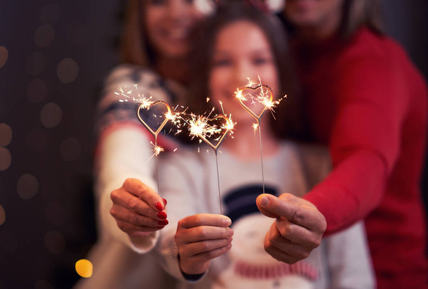 Beautiful family celebrating Christmas and holding sparklers - Foto, imagen