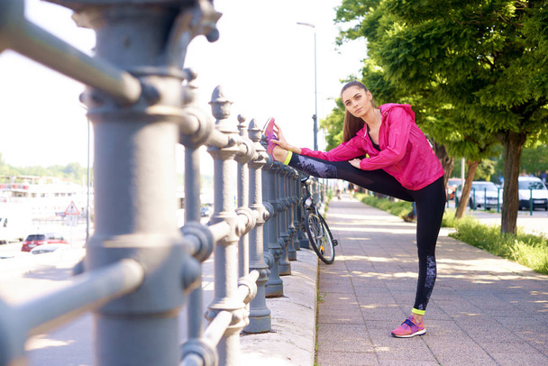 Full length shot of young woman wearing sportswear while stretching after running.  - Valokuva, kuva