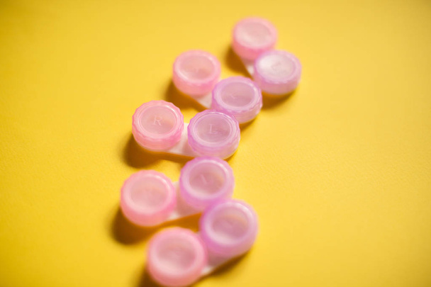 Pink contact lens cases on yellow background - Foto, Imagem