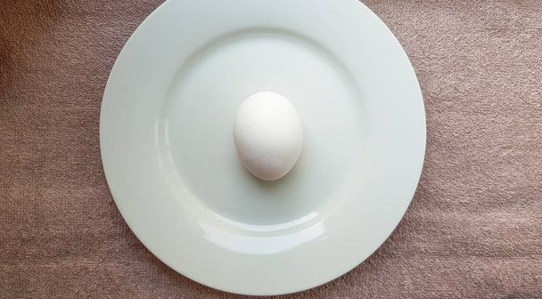 One whole raw chicken white egg on a white plate - Zdjęcie, obraz