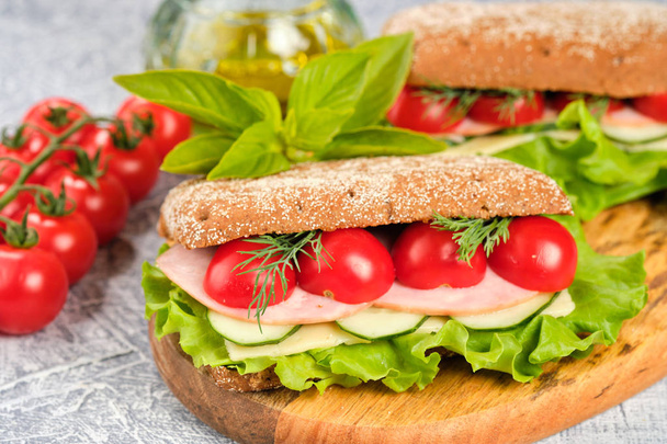 Sandwich with cheese, cucumber and Cherry Tomato on a wooden board. The sandwich is decorated with a lettuce leaf and cherry tomatoes. - Photo, image