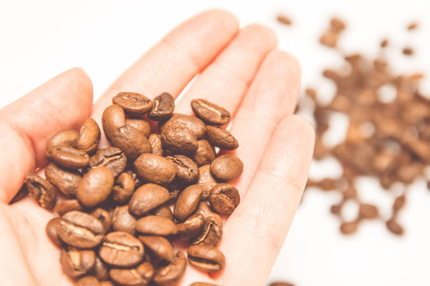 Female hand holds roasted coffee beans - Foto, imagen