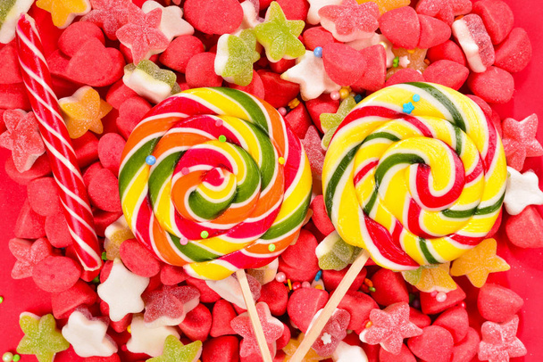 Assorted colorful gummy candies and lollipop on red background.  - Photo, Image