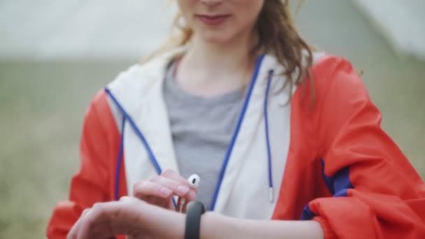 Woman is changing music on her smartwatch and wearing headphones - Záběry, video