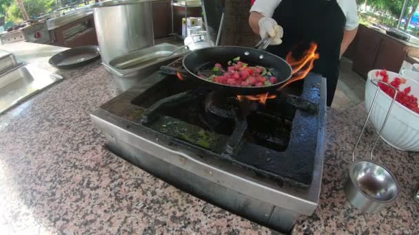 Een vrouwelijk Turks Hotel Cook kookt een omelet met spek en groenten over een open haard. De kok bereidt ontbijt in een pan boven een open haard. - Video