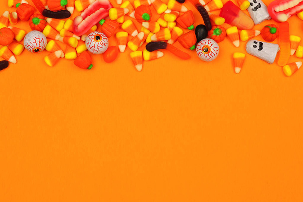 Halloween cukorka felső határ. Fenti nézet narancssárga háttérrel, másolási területtel. - Fotó, kép