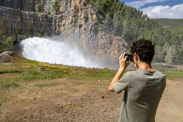 ダムの水出口を撮影する若者 - 写真・画像