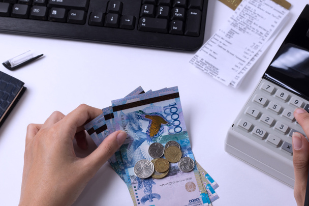 Tenge en el cajero contable en las manos del lugar de trabajo en la oficina. El cajero cuenta el dinero KZT en el lugar de trabajo en Kazajstán
. - Foto, imagen