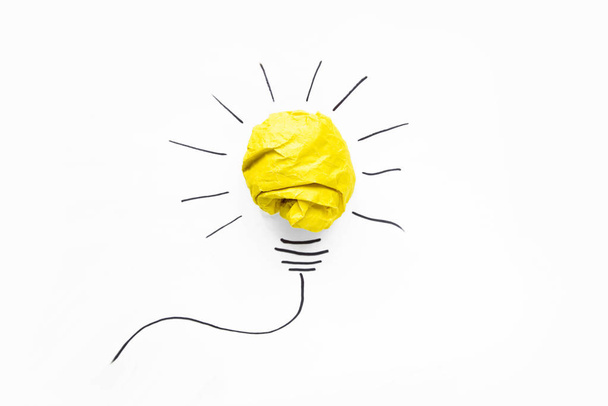 Business ideas. Composition of modern crumpled yellow paper ball and drawing of lamp bulb on white background. Creative and startup concepts. - Foto, Imagen