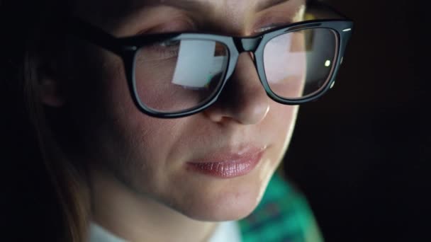 Žena v brýlích, při pohledu na monitor a procházení Internetu. Obrazovka monitoru se odráží v brýle - Záběry, video
