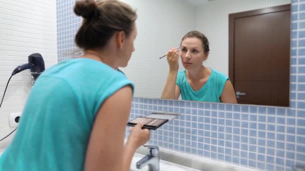 Vrouw doet een ochtend routine-borstels haar tanden, doet make-up en zet haar haar op. - Video