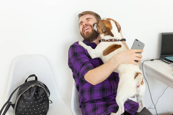 Huisdieren eigenaar concept-jonge man spelen met Jack Russell Terrier puppy binnenshuis - Foto, afbeelding