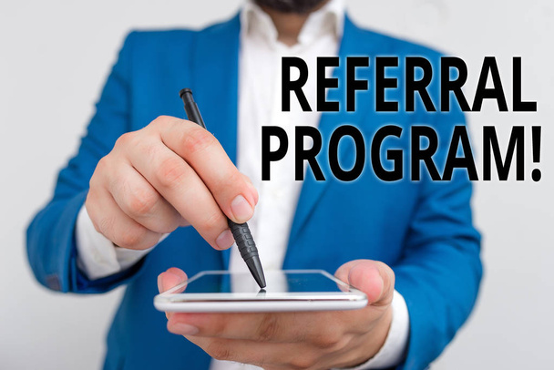 Conceptual hand writing showing Referral Program. Business photo showcasing internal recruitment method employed by organizations Businessman in blue suite with laptop pointing with finger. - Photo, Image