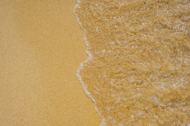 Ondas suaves con espuma de mar en la playa de arena
 - Foto, Imagen