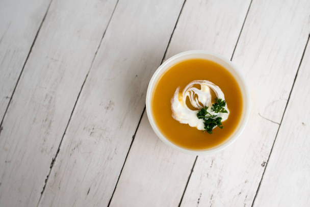 Pumpkin soup with sour cream in white small bowl - Фото, изображение