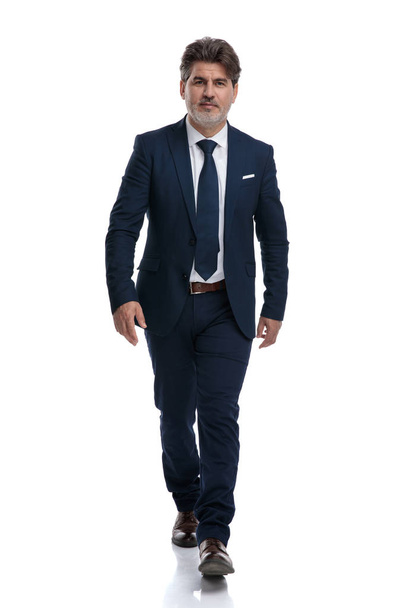 Determined old businessman stepping forward while wearing a blue - Φωτογραφία, εικόνα