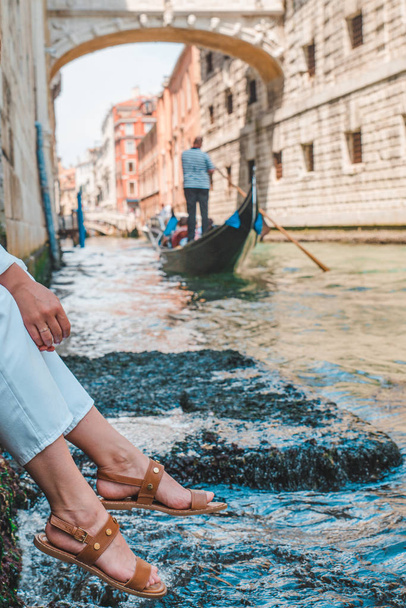 donna seduta al molo di Venezia godendo la vista dei canali con gondole
 - Foto, immagini