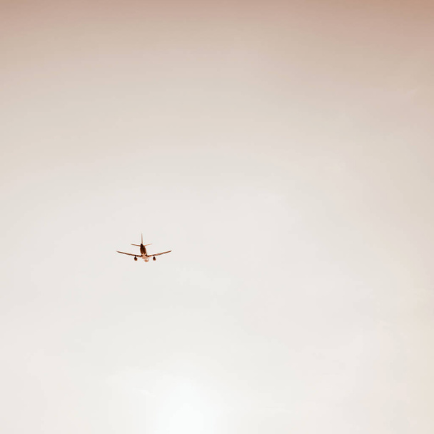 Samolot latający na niebie o zachodzie słońca. Podróże, wakacje i koncepcja wakacje. Vintage i retro odcienie z ciepłym beżowym kolorze filtra. Minimalistyczne tło. - Zdjęcie, obraz