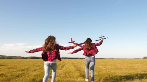 children play toy airplane. teenagers want to become pilot and astronaut. Happy girls run with toy plane at sunset on field. concept of a happy childhood. Girls dream of flying and becoming a pilot. - Footage, Video