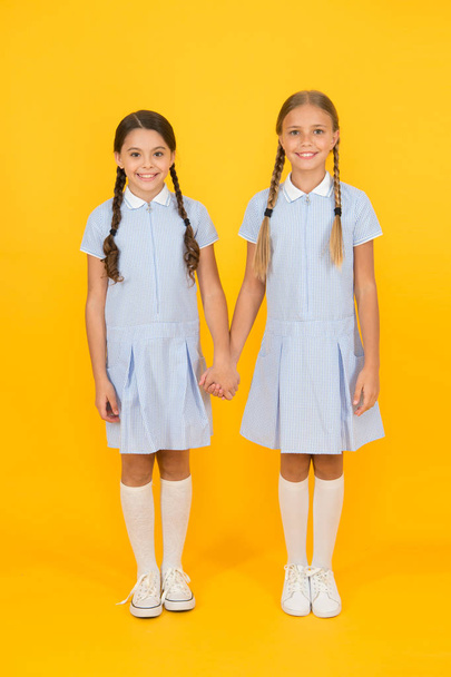 bonded. small girls in school uniform. retro look. children in vintage style. old school. kid fashion. happy friends on yellow background. fashion beauty. childhood happiness. sisterhood concept - Foto, immagini
