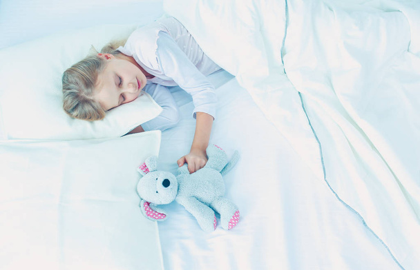 Child little girl sleeps in the bed with a toy teddy bear. - Valokuva, kuva