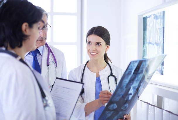 Médicos sonrientes discutiendo diagnóstico de pacientes mirando radiografías en un hospital - Foto, imagen