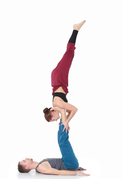 Young athletic couple practicing acroyoga. Balancing in pair. - Foto, imagen