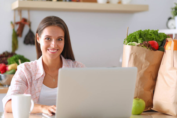 Smiling woman online shopping using tablet and credit card in kitchen . Smiling woman - Photo, Image