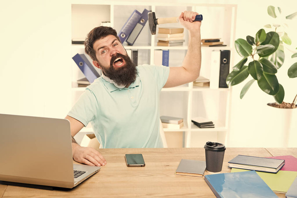 Office life makes him crazy. Businessman with beard and mustache gone mad with hammer in a hand. Frustrated office worker holding hammer poised ready to smash. Angry aggressive businessman in office - Foto, imagen