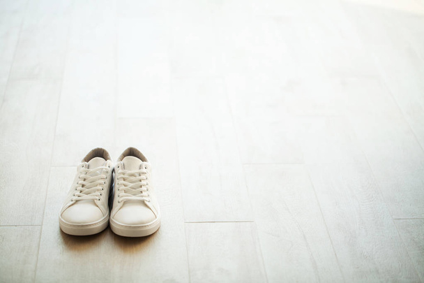 Pair of new stylish white sneakers on wood floor. - Photo, Image