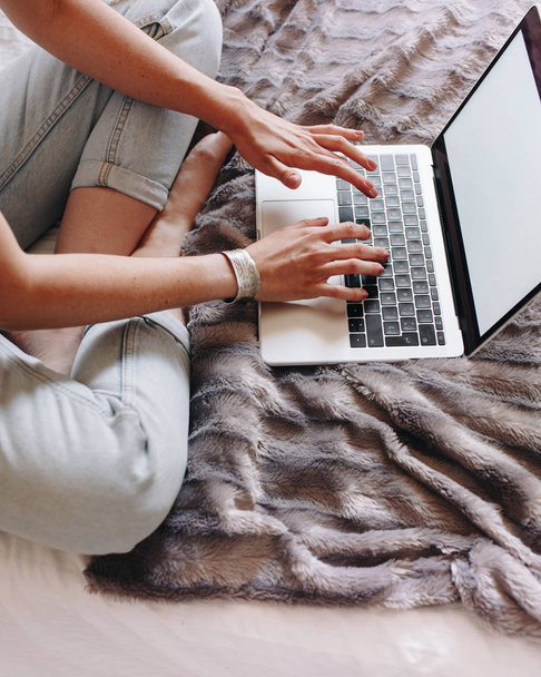 Woman's hands typing on laptop keyboard in the cozy bed. Girl using her laptop in her house - 写真・画像