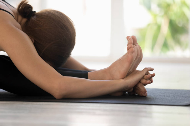 Woman practicing yoga, Seated forward bend, paschimottanasana close up - Photo, image