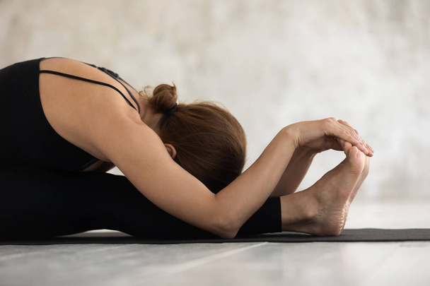 Hermosa mujer practicando yoga, inclinación hacia adelante sentada, paschimottanasana
 - Foto, Imagen
