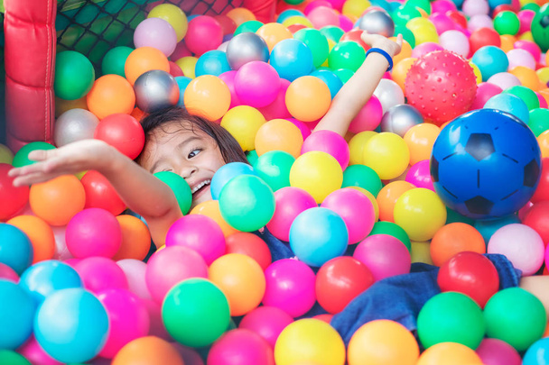 Счастливая маленькая девочка, сидящая в разноцветных шарах. маленькая девочка с c
 - Фото, изображение