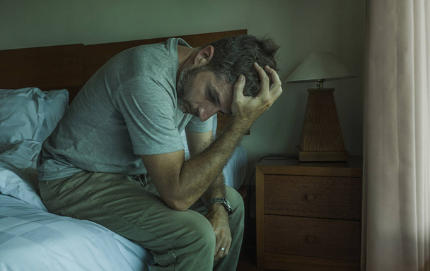 dramatic lifestyle portrait of man sitting depressed on bed crying desperate feeling sad suffering anxiety crisis and depression problem  - Fotografie, Obrázek