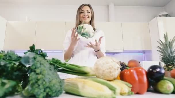 Kitchen and vegetables. The girl holds cauliflower in her hands. - Filmati, video